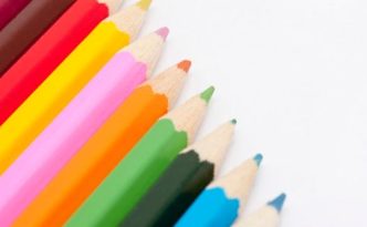 Row of coloured pencil crayons in the colours of the rainbow in a diagonal line with copyspace on a white background